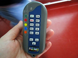 Eine Hand hält ein elektronisches Gerät, einen sogenannten Clicker. Es hat 13 verschiedene farblich markierte Tasten, auf denen je ein Buchstabe und eine Zahl stehen.